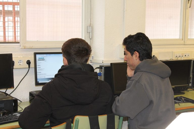 Estudiants i professors col·laborant amb tecnologia en un entorn educatiu